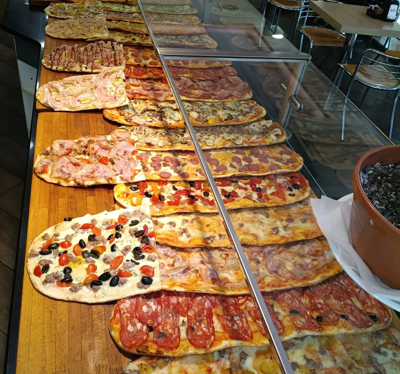 Il banco del pranzo: pizze lunghe e cassoni appena farciti, in prospettiva fino alla sala